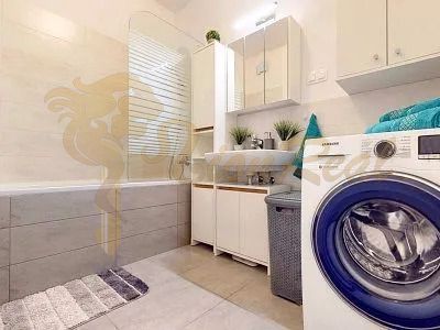 Spacious bathroom in a 3-room apartment with a bathtub and a washing machine, light tiles.