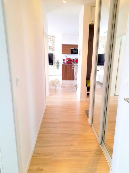 A hallway to the kitchen in a 3-room apartment with a wooden decor floor and built-in wardrobes.