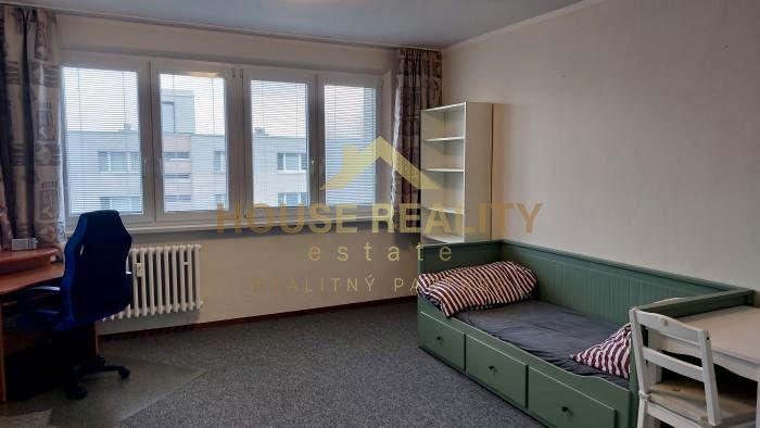 Studio apartment with carpet, bed, desk, and chair.