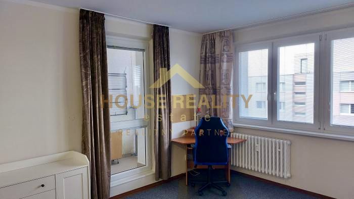 Room in a studio apartment with large windows, an office chair, and a desk.