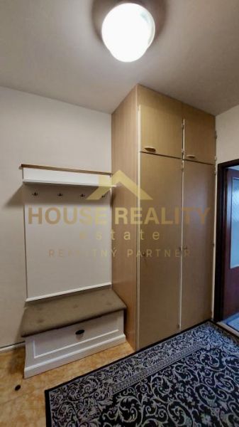 A hallway in a studio apartment with a coat rack, shoe cabinet, and a large wardrobe, flooring with a wooden decor.
