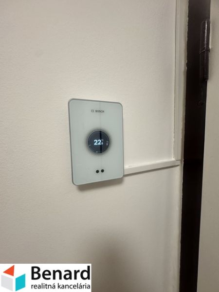 Thermostat on the wall in a 2-room apartment, temperature set to 22°C.