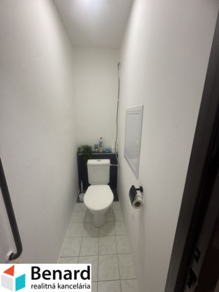 A narrow toilet in a 2-room apartment with white walls and tiles.