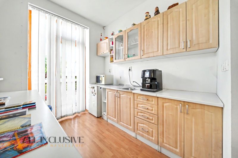 A kitchen with a wooden decor floor and appliances in a 3-room apartment.