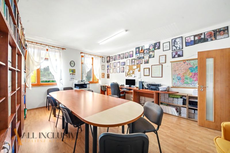 Office of a 3-room apartment with a long table, computers, and shelves with books.