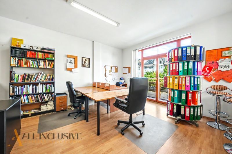 An office with a large window, two chairs, shelves with books, and a floor with a wooden decor.
