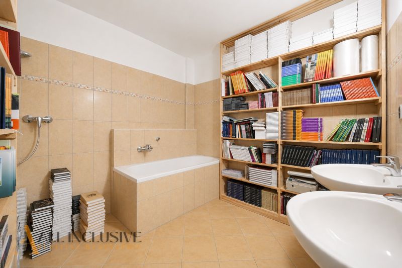 A bathroom with a bathtub and shelves full of books in a 3-room apartment.