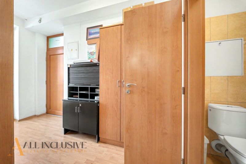 A hallway with a wardrobe, a cabinet, and a toilet, a floor with a wooden decor in a 3-room apartment.