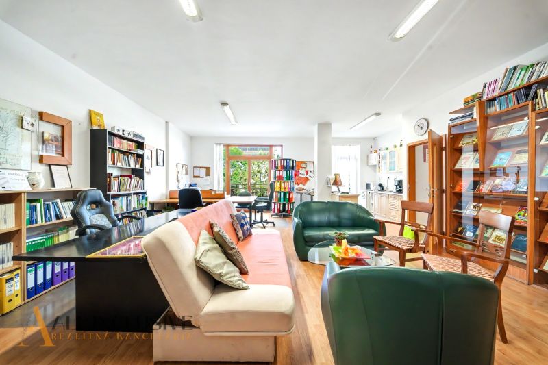 Living room in a three-room apartment with a wooden decor floor, a bookshelf, and a sofa.