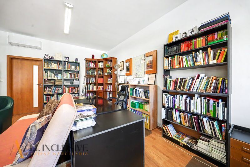 A library and a desk in a 3-room apartment with a wooden decor floor.