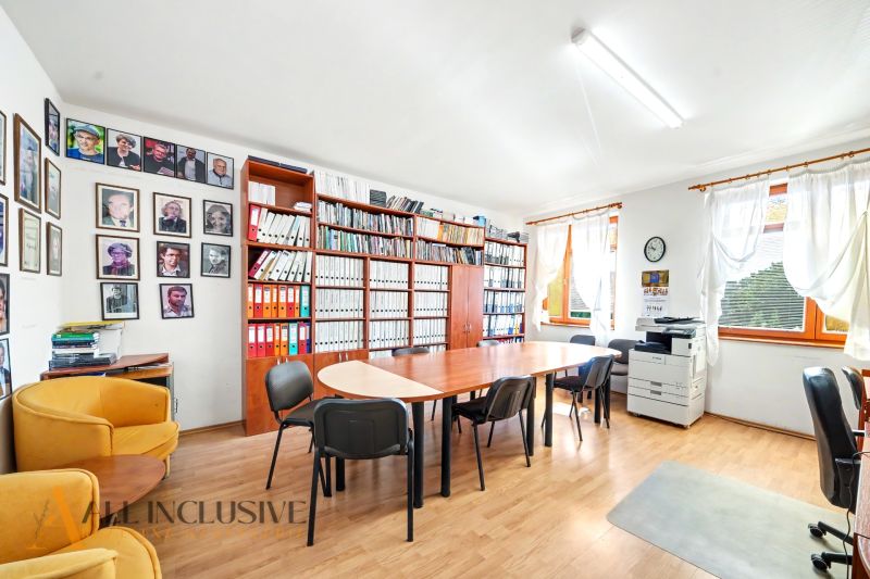An office with a wood-patterned floor, a bookshelf, a desk, a chair, and a copier.