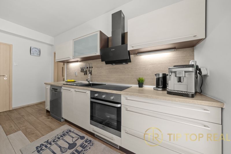 A kitchen in a family house with a wooden decor floor, equipped with a coffee machine and a stove.