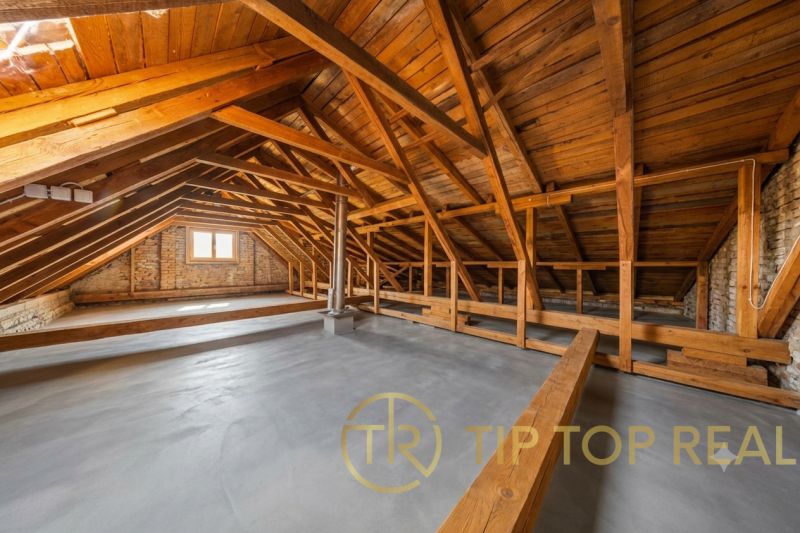 Attic space in a family house with wooden beams and brick walls.
