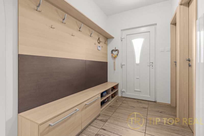 Entrance hallway of a family house with a coat rack wall and white doors.