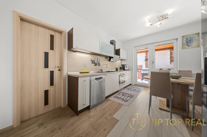 A kitchen in a family house with a kitchen unit, a dining table, and balcony doors.