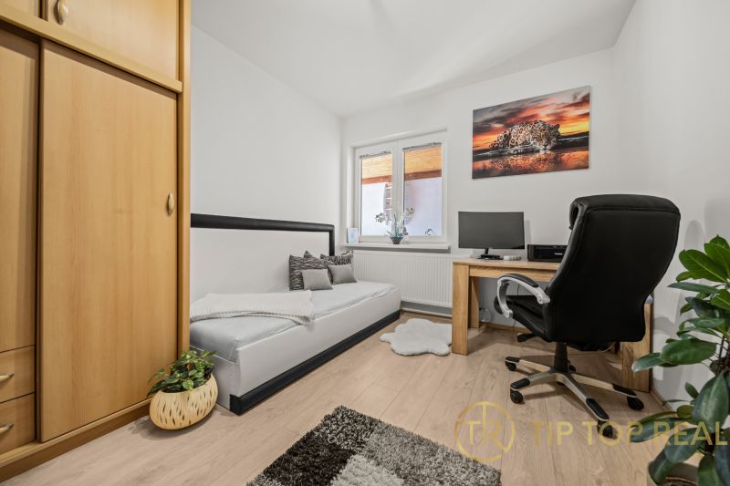 A room in a family house with a wooden decor floor, a table, and a comfortable armchair.