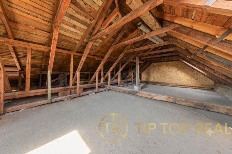 Attic in a family house with wooden beams and a concrete floor.