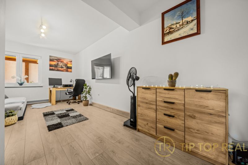 Living room with wood-patterned flooring, a desk, and a television in a family house.