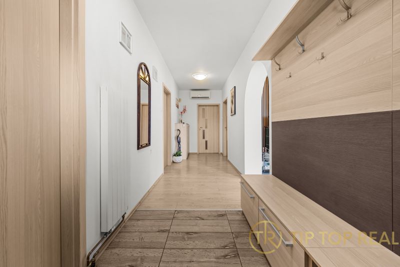 Interior of a family house with a hallway, mirror, and wooden decor flooring.