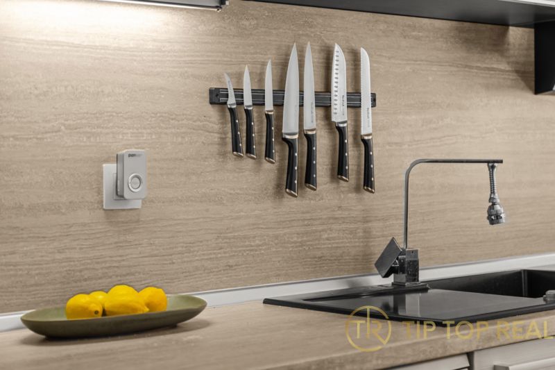 A kitchen in a family house with knives on the wall, a bowl of lemons, and a faucet.