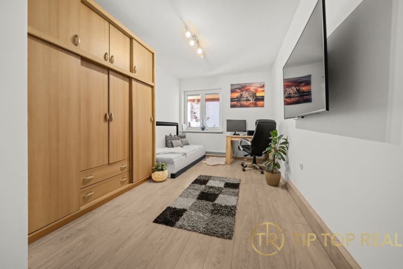 A room in a family house with a desk and a large wardrobe, wooden decor flooring.