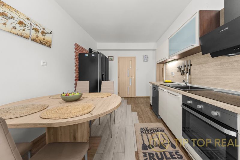 A kitchen in a family house with a dining table and a wooden-patterned floor.