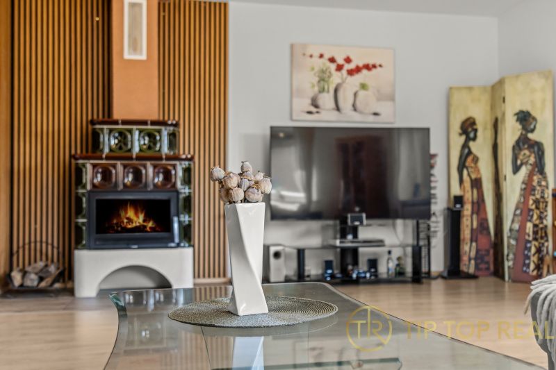 A family house with a tiled stove and a decorative vase on a glass table.