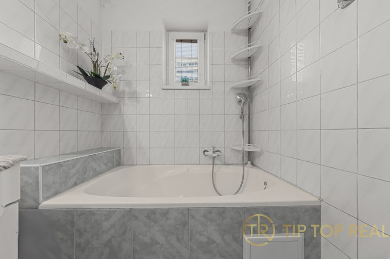 A bathroom with a bathtub and white tiles in a family house.