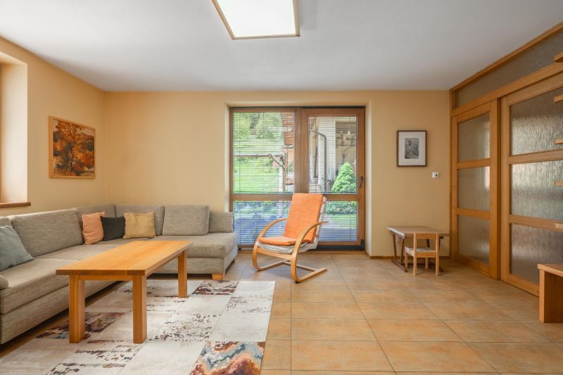 Living room in a family house with a corner sofa, an armchair, and access to the terrace.