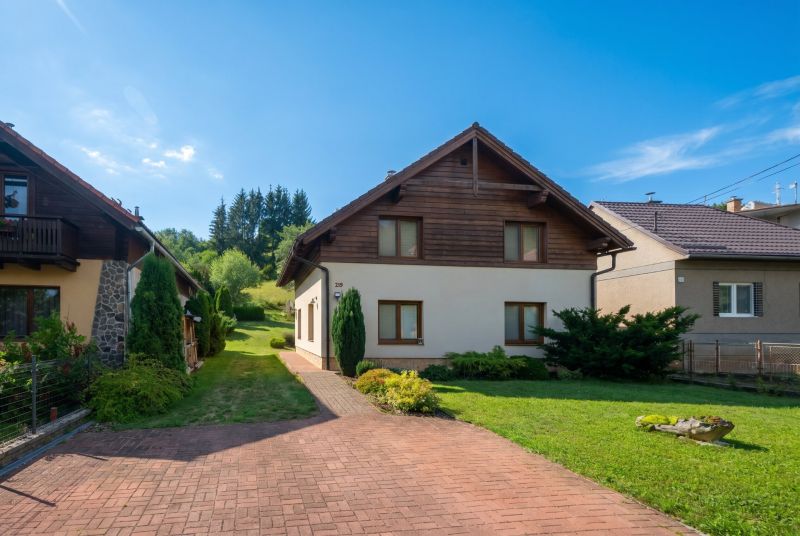 A family house in Horná Lehota surrounded by a garden with a lawn and a driveway.