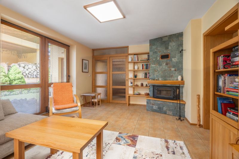 Living room in a family house with a fireplace, a shelf, and a comfortable armchair.