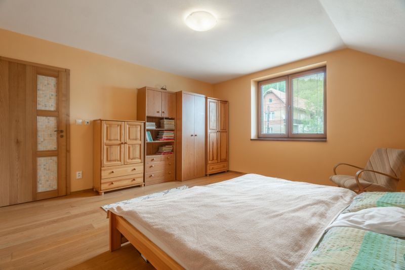 A bedroom in a family house with a wooden decor floor and wooden furniture.