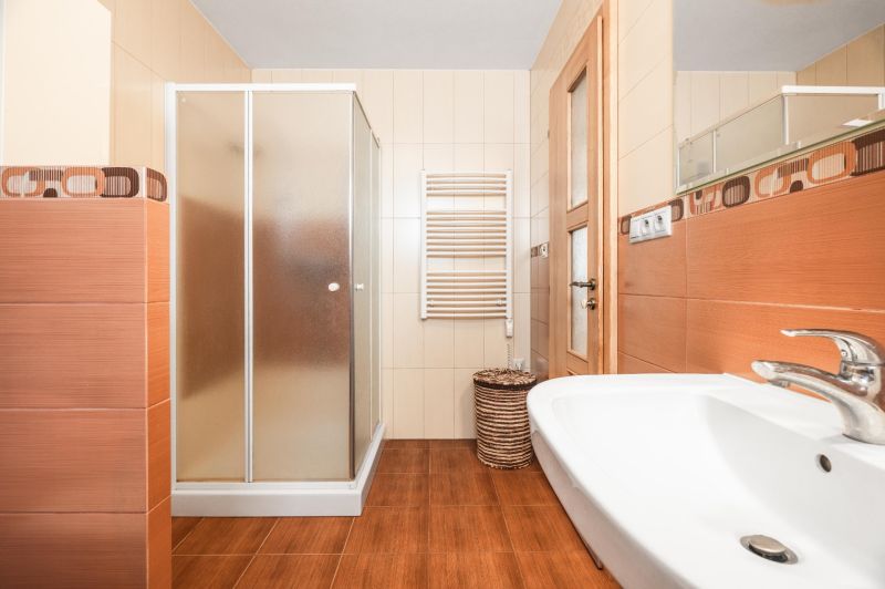 A bathroom in a family house with a wooden decor floor, a shower corner, and a sink.