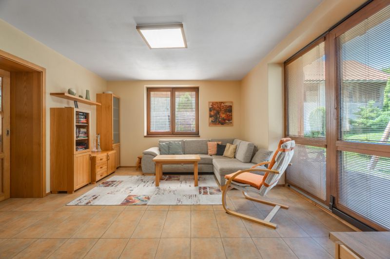 Living room in a family house with a comfortable sofa, wooden furniture, and large windows.