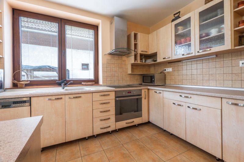 A kitchen in a family house with wooden decor and appliances, light-colored countertop.