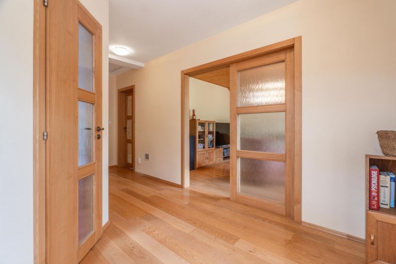 A hallway of a family house with wooden doors and a floor with a wooden decor.