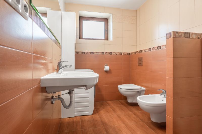 A bathroom in a family house with orange tiles, a sink, and a bidet.