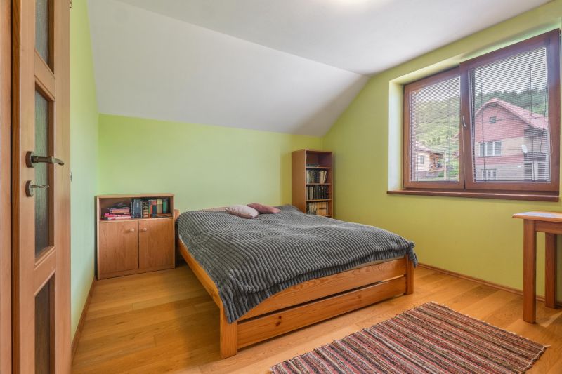 A bedroom in a family house with a wood-patterned floor and a large window.