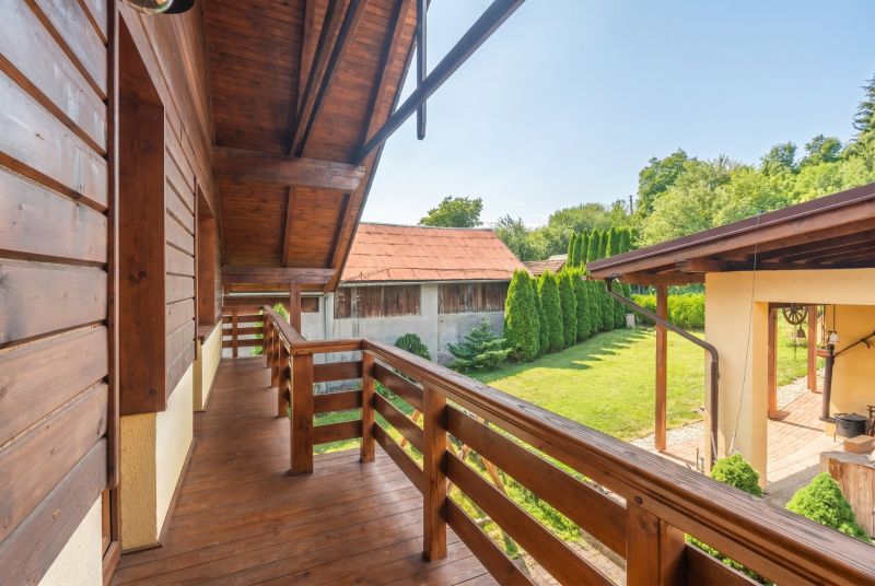 A family house in Horná Lehota with a wooden balcony and a garden with trees.