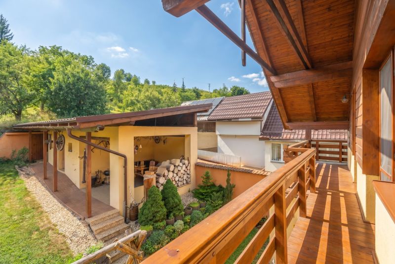 The balcony of a family house in Horná Lehota, wooden railing, garden, and shed.