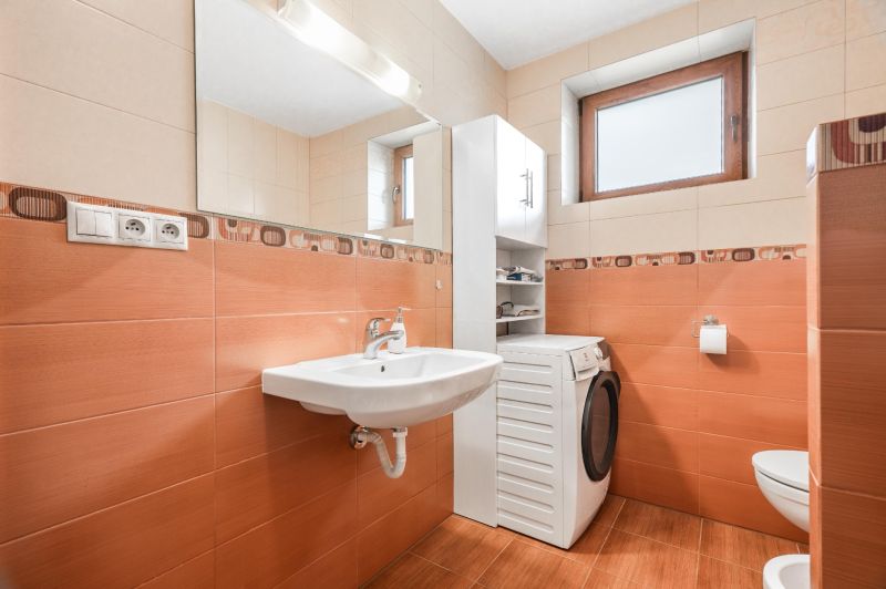 A bathroom in a family house with orange tiles and a washing machine.