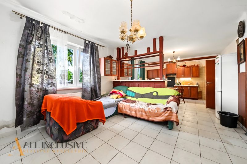 Living room with a large window, a pull-out sofa, and a kitchenette in a family house.
