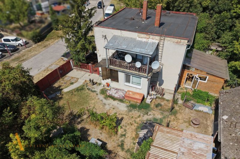 A family house in Bodza with two chimneys, a terrace, and a spacious garden with trees.