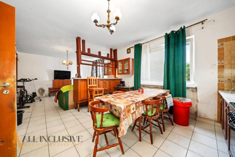 Dining room in a family house with corner cabinets, cream tiles, and green curtains.