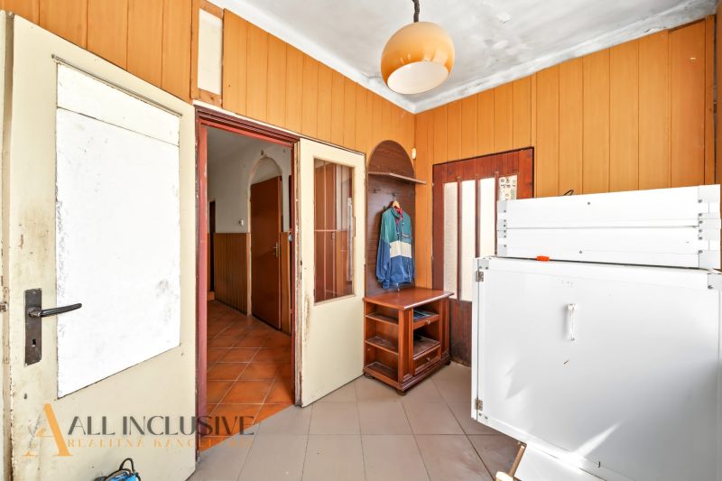 Entrance hallway of a family house with wooden paneling and storage furniture.