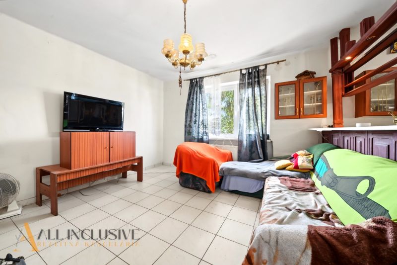 Living room with a TV, sofa, and cabinet in a family house, light through curtains.