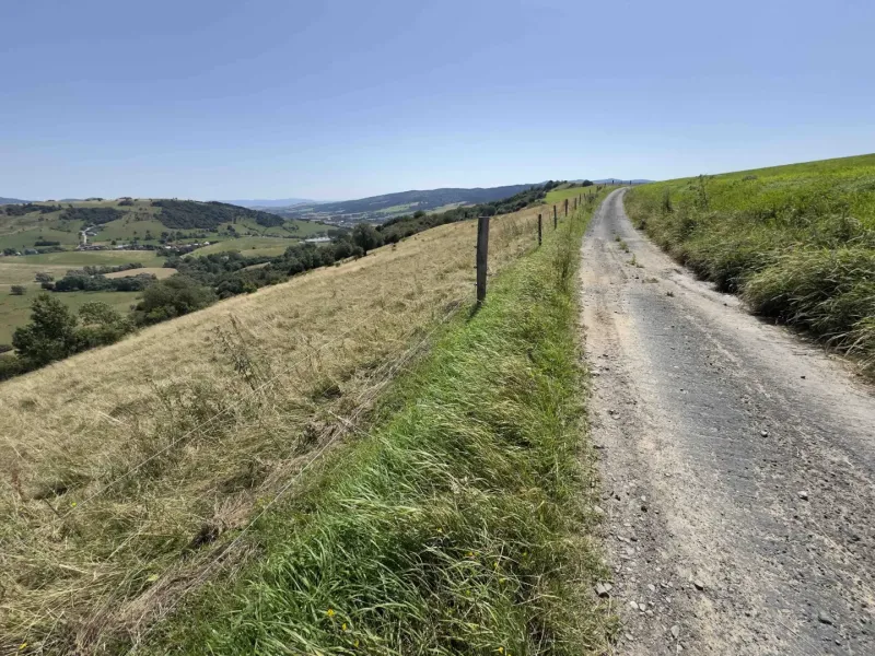 A country road surrounded by meadows and hills in the background, unusual properties in Stará Ľubovňa.