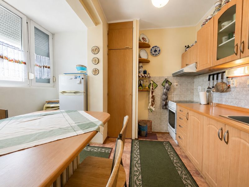A kitchen in a studio apartment with a wood decor and white appliances.