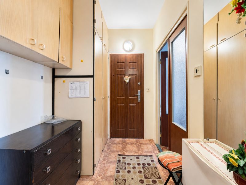 Entrance hall of a one-room apartment with furniture and decorations on a tiled floor.