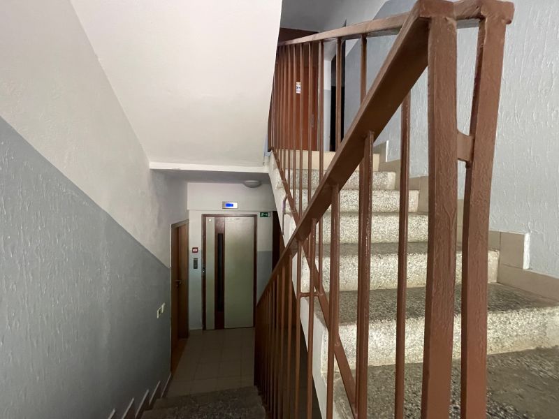 A staircase with a metal railing and access to the elevator on Hany Meličkovej in Bratislava.